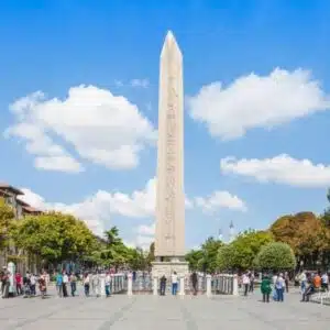 The Obelisk of Theodosius in Istanbul’s Hippodrome Square with tourists gathered around on a bright, sunny day.