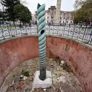 The Serpent Column in Istanbul’s Hippodrome, featuring a twisted bronze design in a circular pit with a surrounding metal fence.
