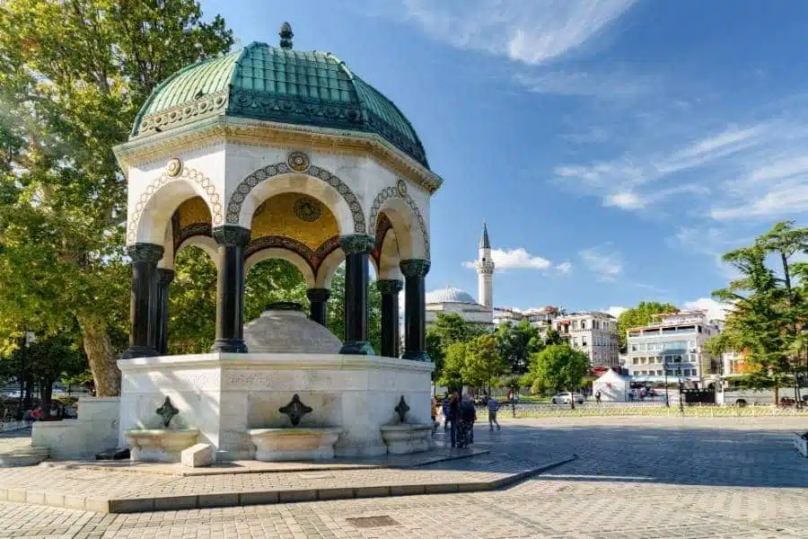 The German Fountain in Istanbul’s Sultanahmet Square with a green domed roof, ornate arches, and a bright, clear sky.