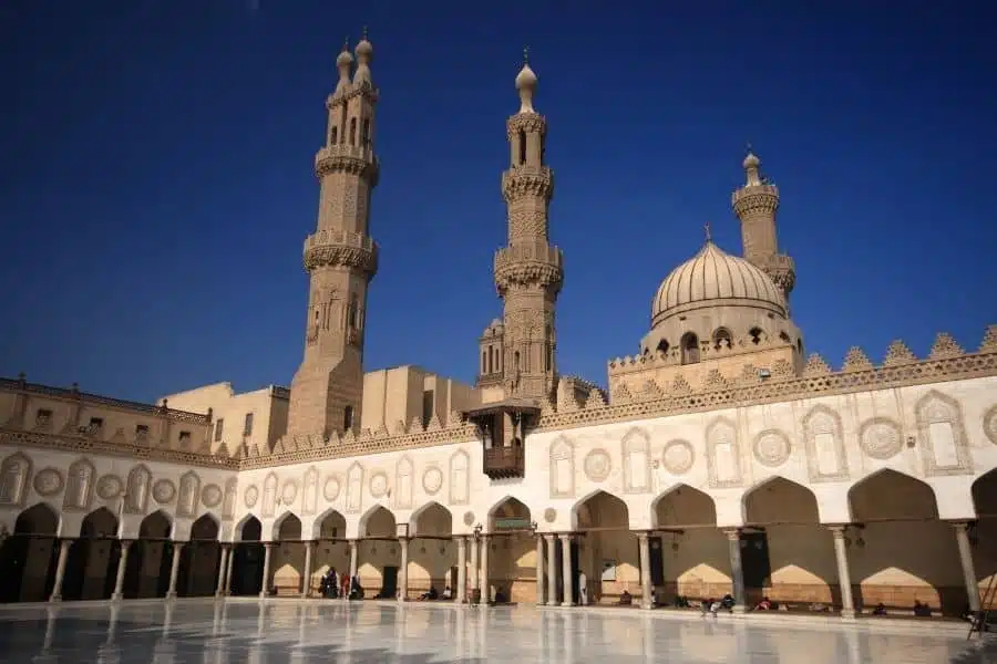 Historic Al-Azhar Mosque in Cairo with ornate minarets and detailed facade under a clear blue sky, symbolizing Islamic architecture.