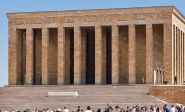 Crowds at Anıtkabir, the grand mausoleum of Mustafa Kemal Atatürk in Ankara, with tall columns and stone facade.