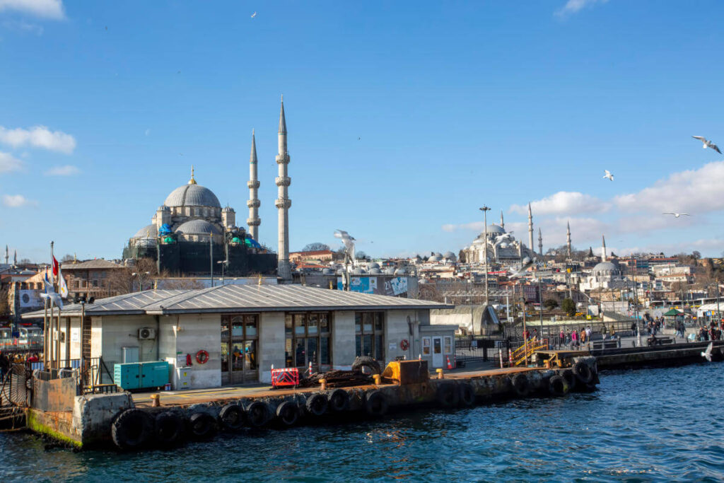 Eminönü Ferry Terminal with ferries docked, framed by Istanbul’s historic mosques under a clear sky.