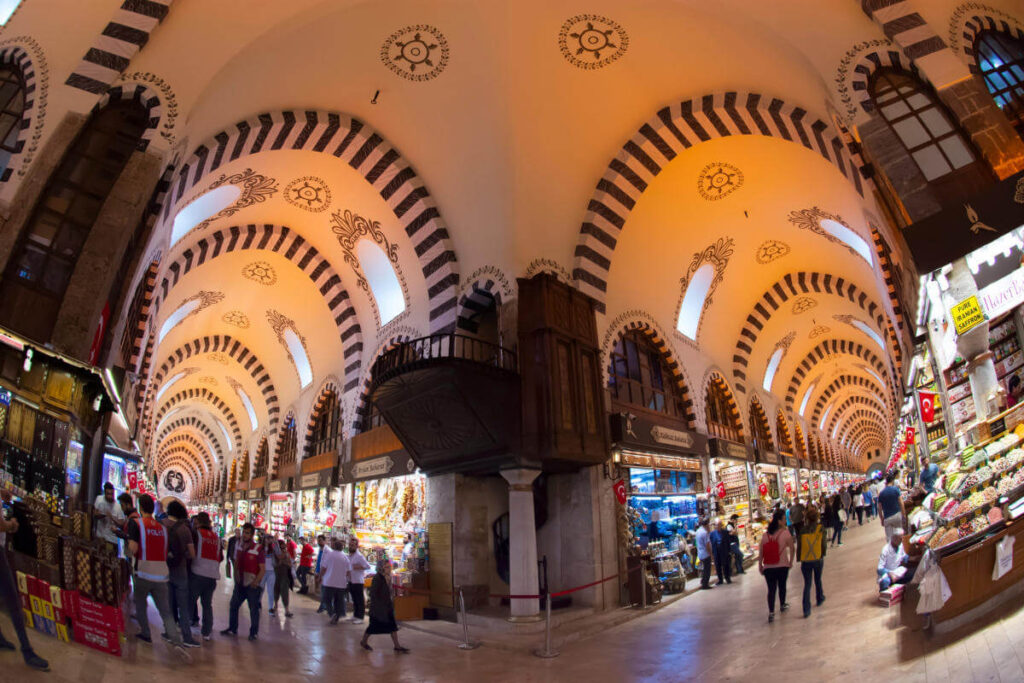Colorful interior of Istanbul’s Spice Bazaar with vibrant spice stalls, hanging lamps, and bustling visitors.