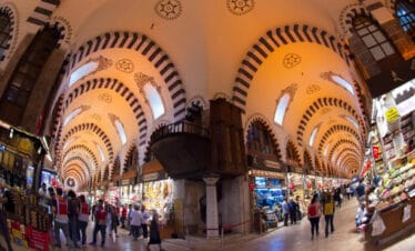 Colorful interior of Istanbul’s Spice Bazaar with vibrant spice stalls, hanging lamps, and bustling visitors.