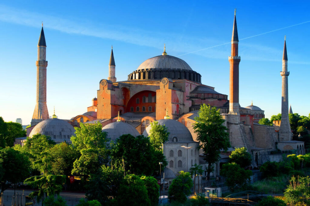 Early morning view of Hagia Sophia with its domes and minarets glowing in sunlight in Istanbul, Turkey.