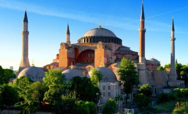 Early morning view of Hagia Sophia with its domes and minarets glowing in sunlight in Istanbul, Turkey.
