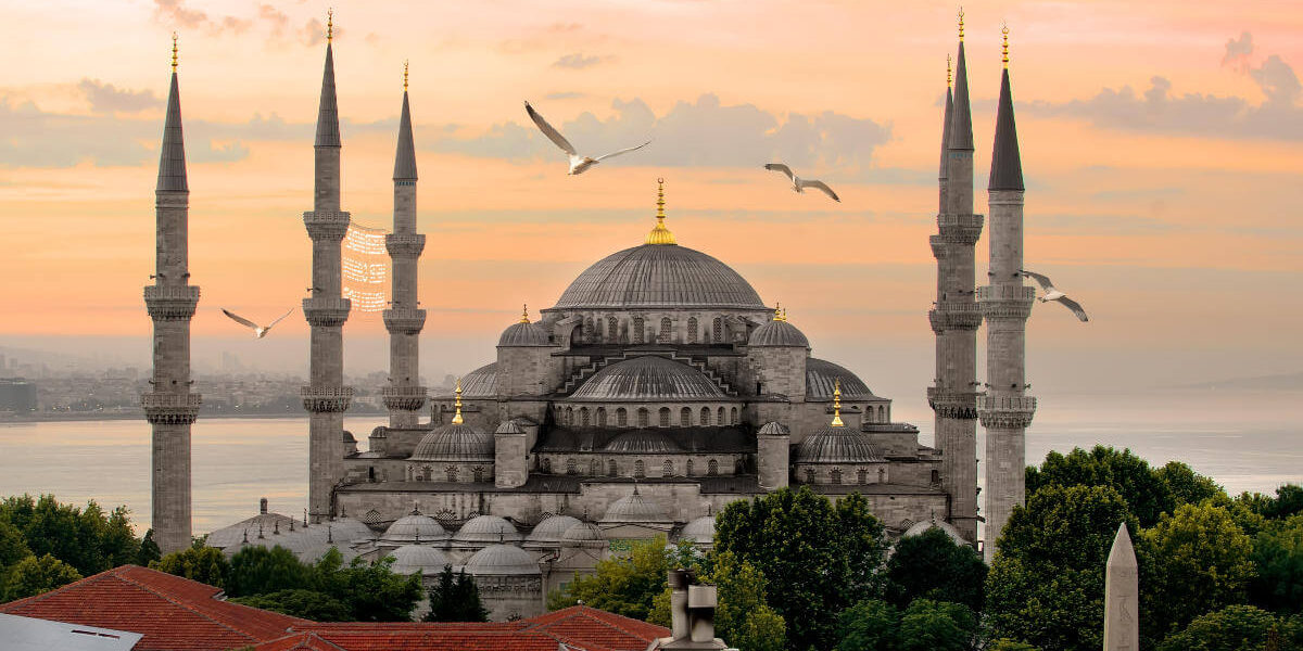 Majestic Blue Mosque with six minarets and seagulls flying above at sunset in Istanbul, Turkey.