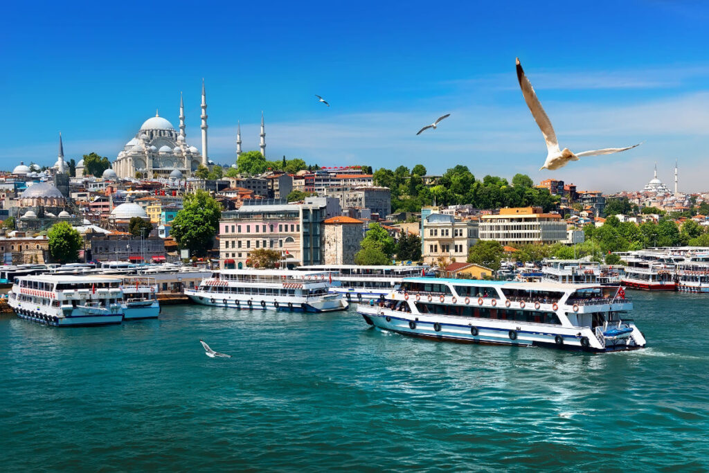 Passenger ferries on the Bosphorus with Istanbul’s skyline and Suleymaniye Mosque under a clear blue sky.