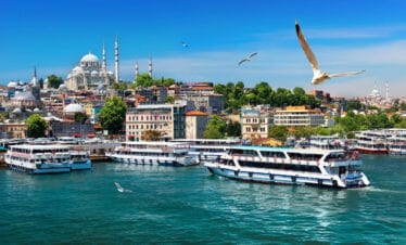 Passenger ferries on the Bosphorus with Istanbul’s skyline and Suleymaniye Mosque under a clear blue sky.
