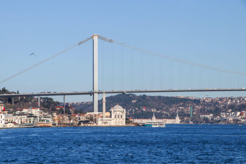 Ortaköy Mosque by the Bosphorus with the Bosphorus Bridge in the background under a vibrant Istanbul sky.