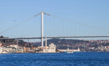 Ortaköy Mosque by the Bosphorus with the Bosphorus Bridge in the background under a vibrant Istanbul sky.