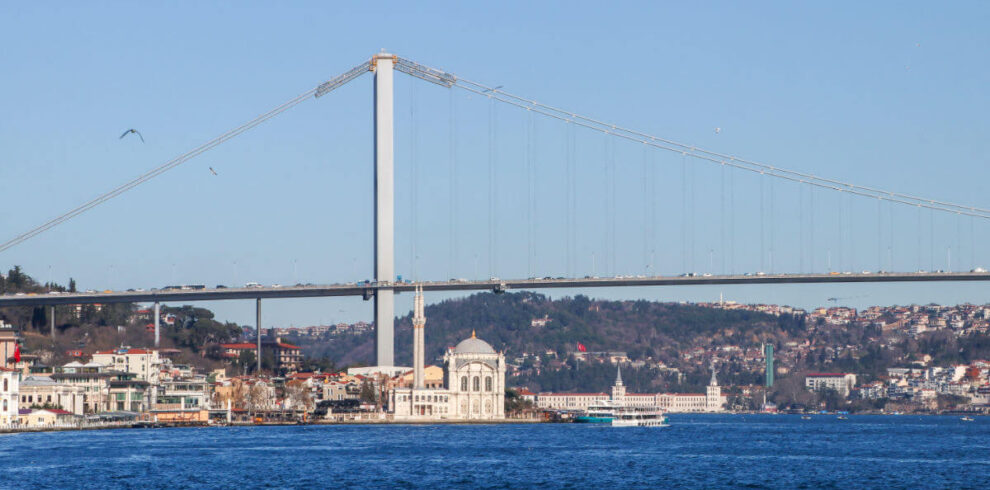 Ortaköy Mosque by the Bosphorus with the Bosphorus Bridge in the background under a vibrant Istanbul sky.