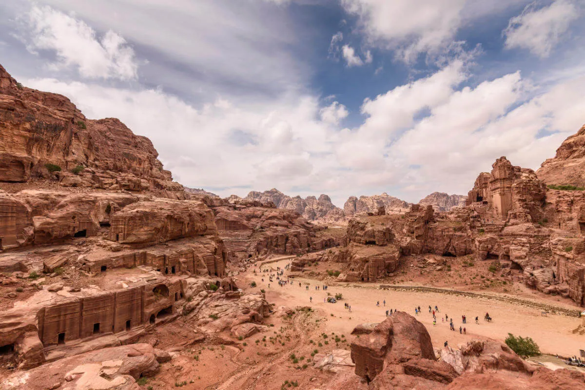 Panoramic view of Petra’s rock-cut city in Jordan, showcasing carved facades, sandstone cliffs, and ancient Nabatean tombs.