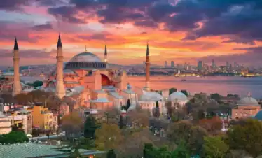 Scenic view of the Hagia Sophia Grand Mosque in Istanbul at sunset overlooking the Bosphorus Strait and city skyline.