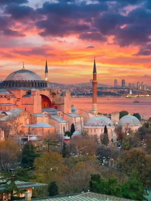 Scenic view of the Hagia Sophia Grand Mosque in Istanbul at sunset overlooking the Bosphorus Strait and city skyline.