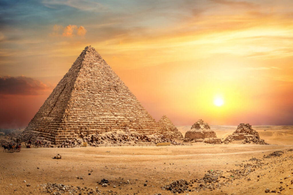 Great Pyramid of Giza in Egypt illuminated by a golden sunset, with smaller surrounding pyramids and desert landscape.
