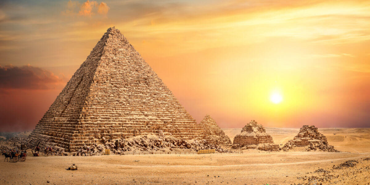 Great Pyramid of Giza in Egypt illuminated by a golden sunset, with smaller surrounding pyramids and desert landscape.