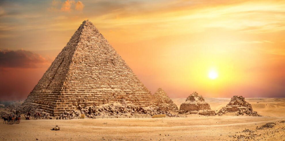 Great Pyramid of Giza in Egypt illuminated by a golden sunset, with smaller surrounding pyramids and desert landscape.