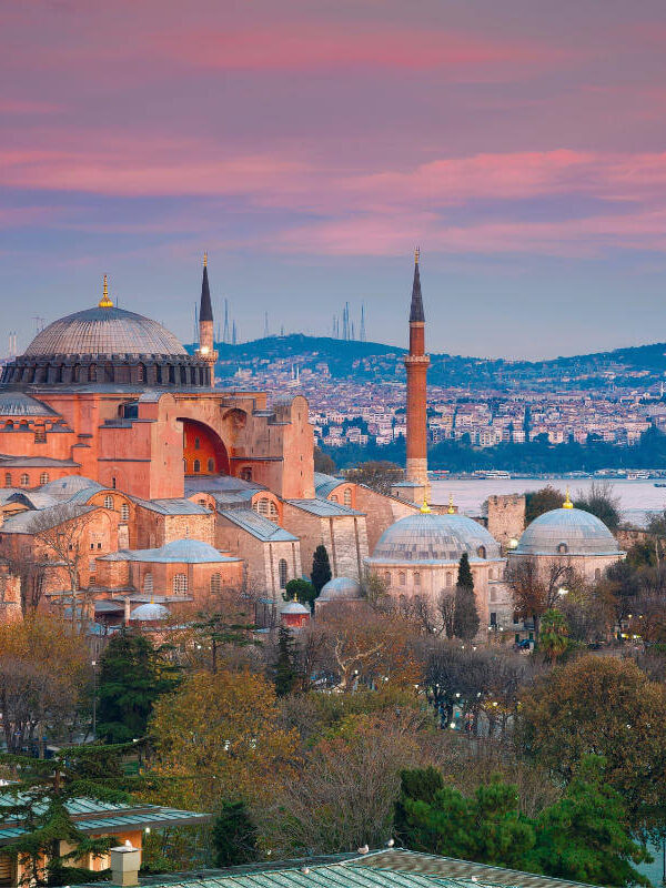 Historic Hagia Sophia mosque with domes and minarets under a pink sunset sky in Istanbul, Turkey.