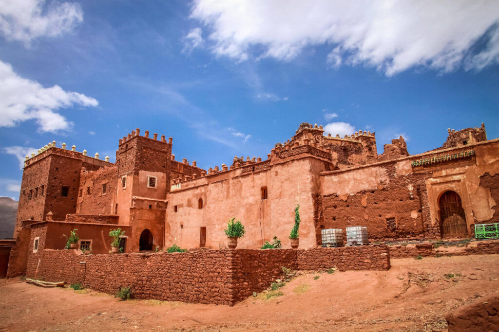 Traditional red clay Kasbah architecture in Skoura, Morocco, showcasing fortified walls and ornate towers.