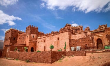 Traditional red clay Kasbah architecture in Skoura, Morocco, showcasing fortified walls and ornate towers.