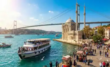 Scenic view of Ortaköy Mosque and Bosphorus Bridge in Istanbul with a sightseeing ferry on the water.