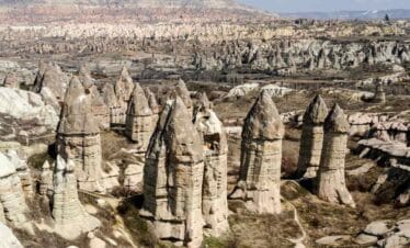 Unique cone-shaped rock formations known as fairy chimneys rise from Cappadocia’s arid valley under clear skies.
