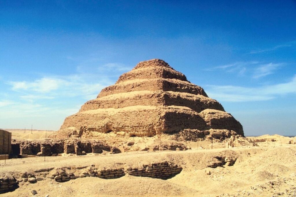 Ancient Step Pyramid of Djoser in Saqqara, Egypt, made of limestone and surrounded by desert ruins.