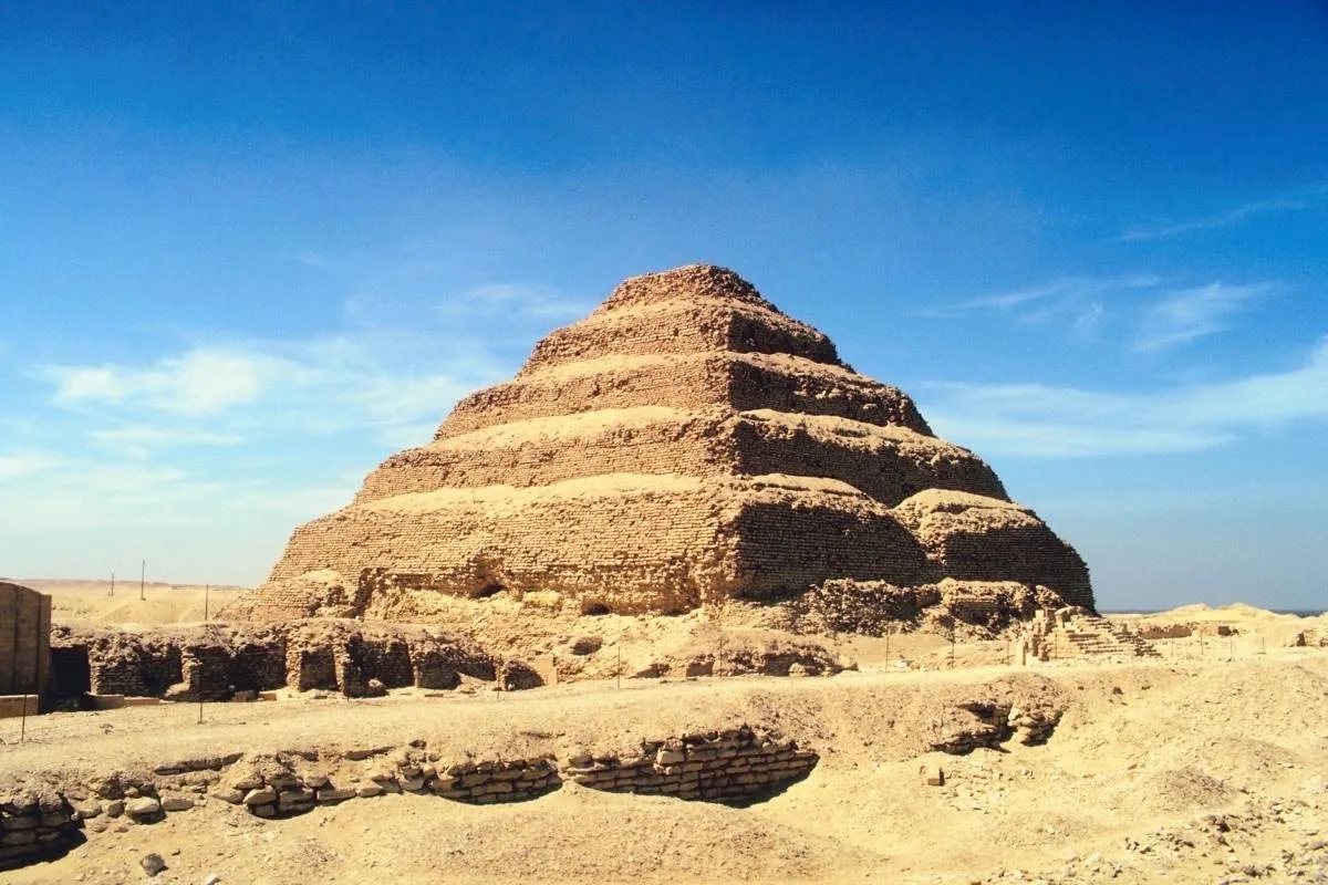 Ancient Step Pyramid of Djoser in Saqqara, Egypt, made of limestone and surrounded by desert ruins.