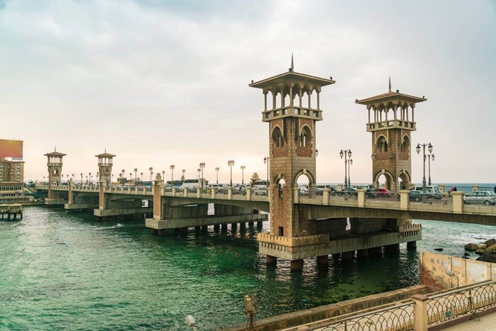Stanley Bridge with arched towers spans turquoise Mediterranean waters in Alexandria, Egypt during sunset.