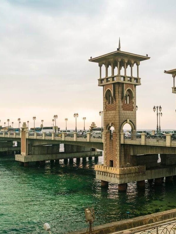 Stanley Bridge with arched towers spans turquoise Mediterranean waters in Alexandria, Egypt during sunset.