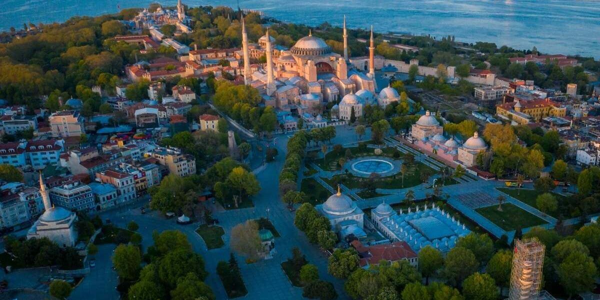 Aerial view of Hagia Sophia in Istanbul surrounded by historic buildings and Bosphorus Strait at dusk.