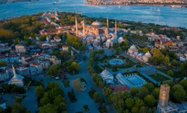 Aerial view of Hagia Sophia in Istanbul surrounded by historic buildings and Bosphorus Strait at dusk.