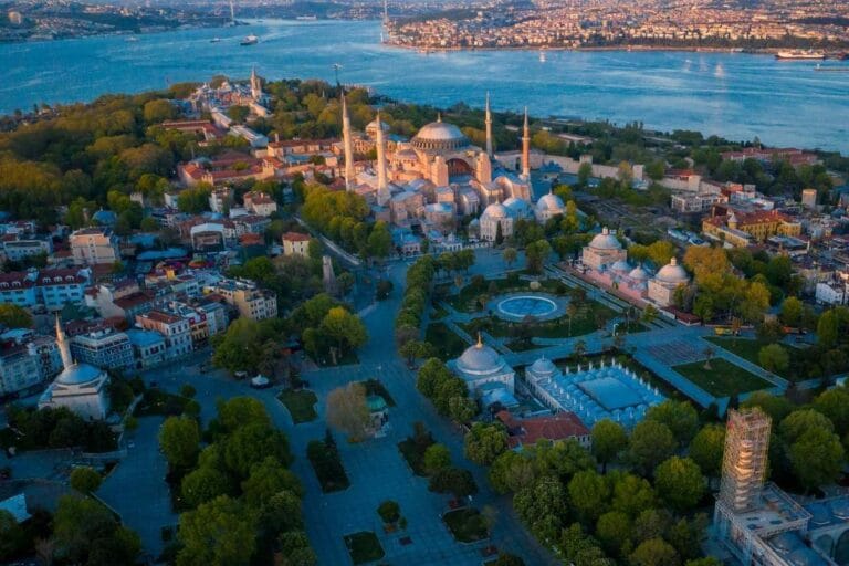 Aerial view of Hagia Sophia in Istanbul surrounded by historic buildings and Bosphorus Strait at dusk.