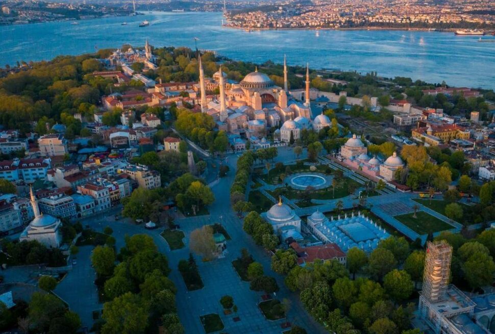 Aerial view of Hagia Sophia in Istanbul surrounded by historic buildings and Bosphorus Strait at dusk.