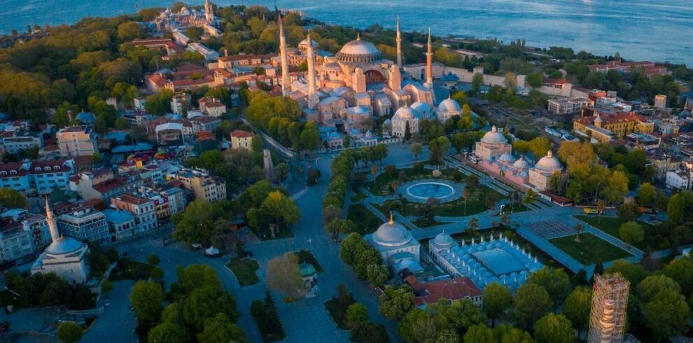 Aerial view of Hagia Sophia in Istanbul surrounded by historic buildings and Bosphorus Strait at dusk.