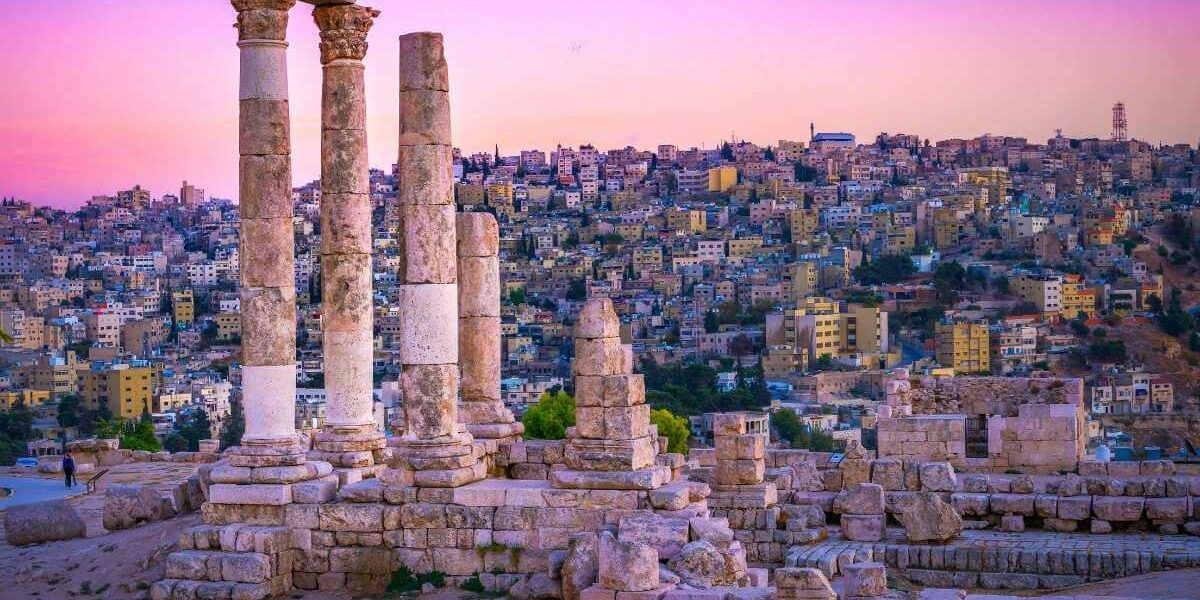 Ancient Roman columns of the Temple of Hercules in Amman, Jordan with cityscape at sunset in vibrant colors