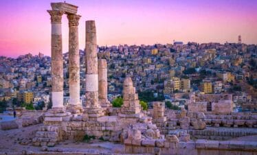 Ancient Roman columns of the Temple of Hercules in Amman, Jordan with cityscape at sunset in vibrant colors