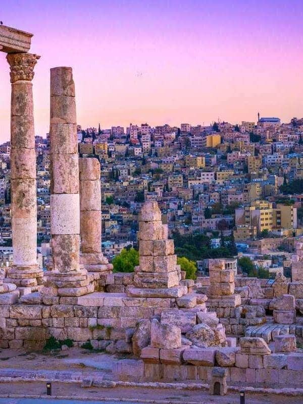 Ancient Roman columns of the Temple of Hercules in Amman, Jordan with cityscape at sunset in vibrant colors