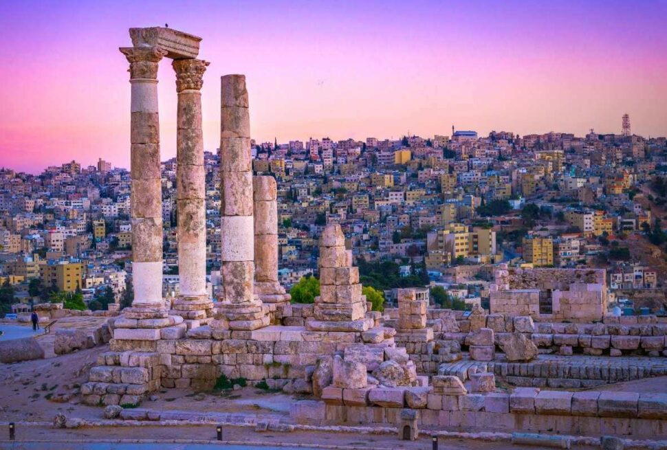 Ancient Roman columns of the Temple of Hercules in Amman, Jordan with cityscape at sunset in vibrant colors