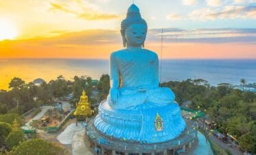 Phuket Big Buddha statue overlooking the Andaman Sea at sunset with golden sky and tranquil ocean views.