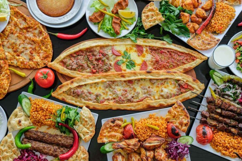 Assorted Turkish dishes including pide, kebabs, bulgur, and salads displayed in a colorful and abundant meal spread.