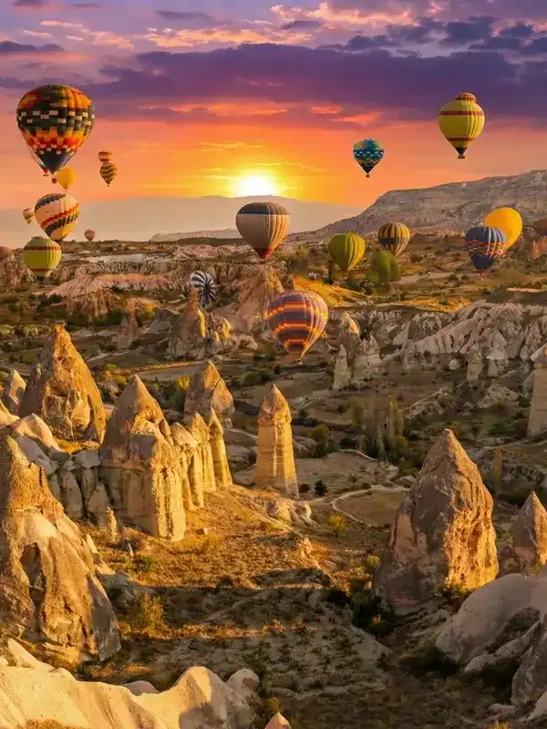 Stunning sunrise view of hot air balloons flying over fairy chimneys in Cappadocia, taken from a traditional rooftop terrace. A highlight of best Cappadocia tours.