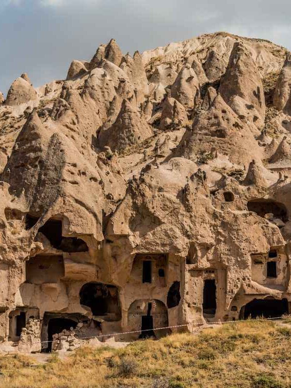 Ancient cave dwellings carved into cone-shaped rock formations at Zelve Open Air Museum in Cappadocia, Turkey.