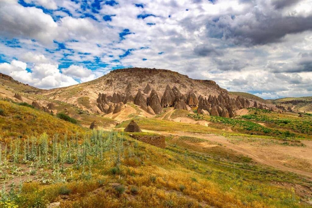Unique rock formations and cave dwellings carved into hillsides in Yaprakhisar under a partly cloudy sky.