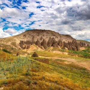 Unique rock formations and cave dwellings carved into hillsides in Yaprakhisar under a partly cloudy sky.