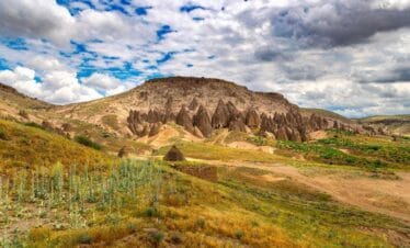 Unique rock formations and cave dwellings carved into hillsides in Yaprakhisar under a partly cloudy sky.