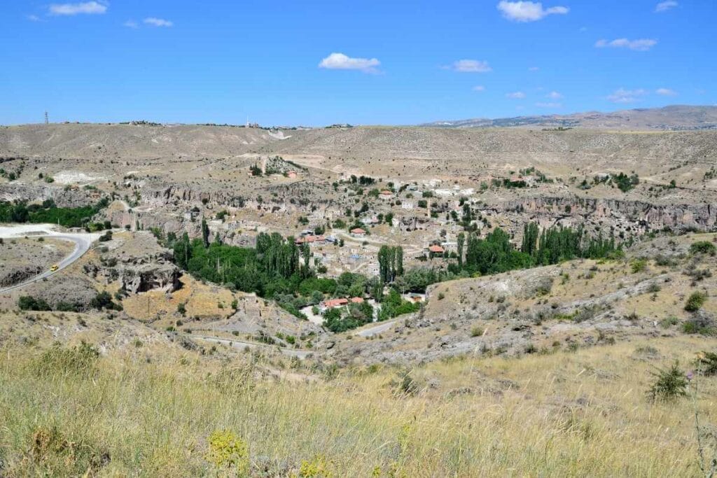 Riverside view of Belisirma Village in Cappadocia, with stone houses and lush greenery along the Melendiz River.