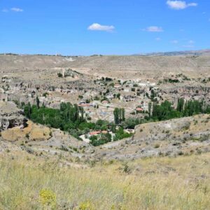 Riverside view of Belisirma Village in Cappadocia, with stone houses and lush greenery along the Melendiz River.