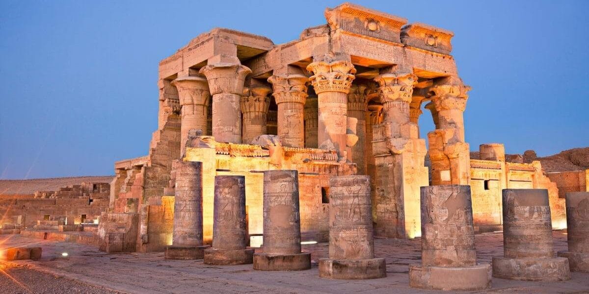 Temple of Kom Ombo in Egypt illuminated at dusk, showcasing ancient stone columns with detailed carvings.